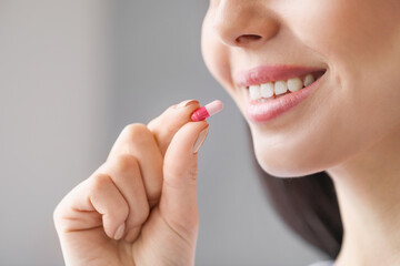 Wall Mural - Beautiful young woman taking pills at home, closeup