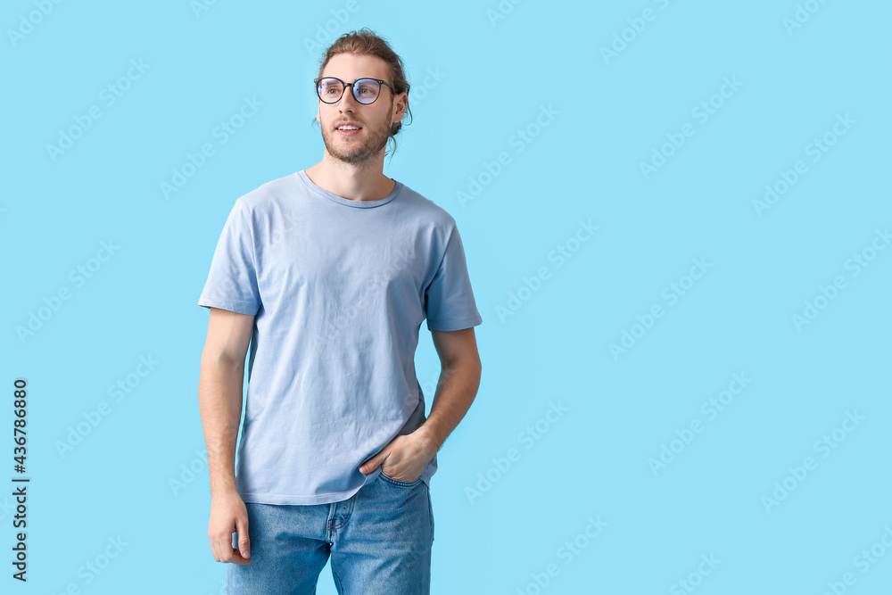 Young man wearing eyeglasses on color background