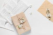 Beautiful blooming branches, gift box and newspaper on light background