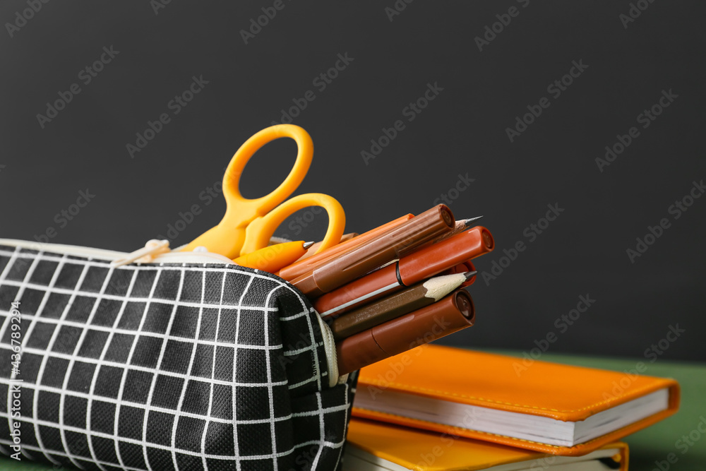 Pencil case and stationery on dark background