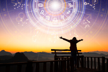 woman raising hands looking at the sky. astrological wheel projection, choose a zodiac sign. trust h