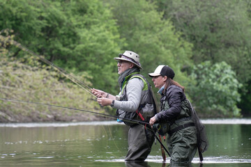 fishing guide with a young woman fly fishing for trout in a clear river