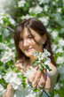 Beautiful woman with cherry flowers in spring garden, outfocus on face. Focus on flower 