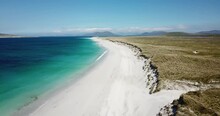 4k Aerial Footage Of West Beach, Berneray, Outer Hebrides, Scotland. Sunny Day, White Sand, Turquoise And Blue Sea Water, Sand Dunes With Green Grass, Blue Sky And Light Cloud, Mountains In Distance.