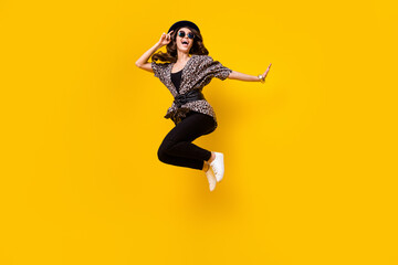 Wall Mural - Photo of crazy funky young woman jump up look empty space wear black hat isolated on yellow color background