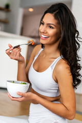 Beautiful fit woman eating healthy salad after fitness workout