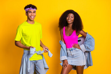 Poster - Portrait of attractive cheerful couple wearing retro denim look posing isolated over bright yellow color background