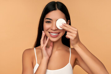 young woman cleans beauty face using cotton pads, cleansing lotion and face toner to remove makeup. 