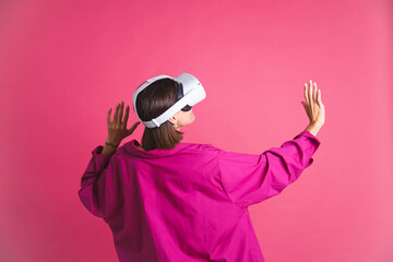 beautiful fit tanned sporty woman in shirt in virtual reality glasses on pink background back ro cam