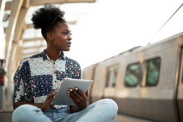 Happy young woman waiting for the train. African woman waiting for a subway train..