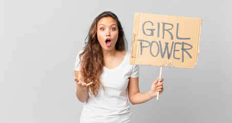 Wall Mural - young pretty woman feeling extremely shocked and surprised and holding a girl power banner