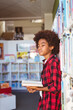 © wavebreak3 - Happy african american schoolboy reading book standing in school library, looking away