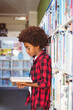© WavebreakMediaMicro - Happy african american schoolboy reading book standing in school library