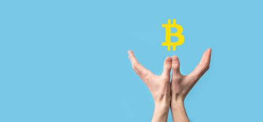 Male hand holding a bitcoin icon on blue background. Bitcoin Cryptocurrency Digital Bit Coin BTC Currency Technology Business Internet Concept.