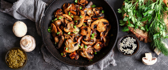 Wall Mural - Roasted mushrooms with onion in frying pan on a dark background. Top view. Food banner