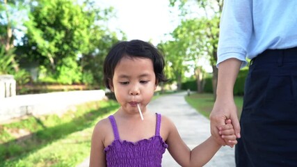 Wall Mural - Adorable girl holding her mother hand walking at village.