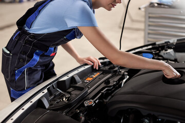 Wall Mural - Female auto mechanic examine car engine breakdown problem in front of automotive vehicle car hood. Safety technical inspection care check service maintenance for customer before long road trip