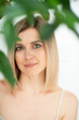 © Khorzhevska - Beautiful calm middle aged woman with green plant, natural light. Anti-aging and beauty treatment.
