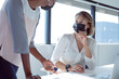 © Wavebreak Media - Two diverse smiling businesswomen wearing face masks, working together, using laptop, talking