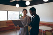 © Wavebreak Media - Two diverse businesswoman standing, talking, using laptop at work