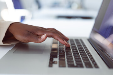 Close up of hands of african american businesswoman using laptop