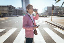 Asian Businessman Using Smartphone Drinking Takeaway Coffee Crossing City Street