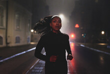 Fit Woman Running On A Street At Night