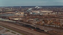 Wide Aerial Push In Shot Of Operating Steelyard In Cleveland Ohio With Train Cars On Railroad Tracks In Foreground.