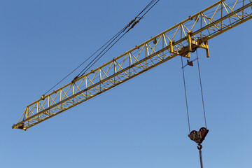 Hydraulic luffing jib tower cranes and workers being poured concrete into foundation. Cement pouring into formwork of building at construction site. Tower cranes constructing a new residential build