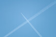 Low angle shot of intersecting plane trails in the blue sky forming an 