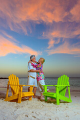 Wall Mural - Romantic older couple at the beach hugging with beach chairs at sunset