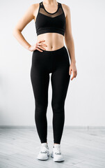 Female activewear. Yoga apparel. Outfit for branding. Workout design clothes. Front view of slim athletic woman body in blank label black mesh crop top bra leggings on light background.