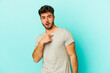 © Asier - Young caucasian man isolated on blue background surprised pointing with finger, smiling broadly.