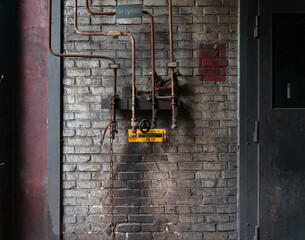 Wall Mural - A closeup of an old brick wall with rusty pipes, cog and chain