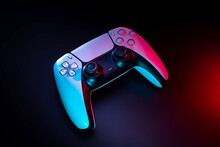 Modern White Gamepad Illuminated In Red And Blue. Game Controller For Video Games And E-sports On A Dark Back