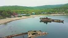 View From Above. The Camera Pans Over Two Sunken Wooden Ships Near The Shore. Wrecked And Sunken Sailing Ships Lie Aground Off The Coast Of The Village Of Vityaz In The Primorsky Region.