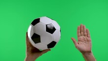 A Male Hand Holds A Classic Black And White Soccer Ball And The Second Hand Shows A Hand With An Open Palm, Free Kick, Isolated On A Studio Green Screen Of Key Chromaticity. Slow Motion. Close Up.