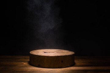 empty circular wooden cutiing board with smoke float up on dark background