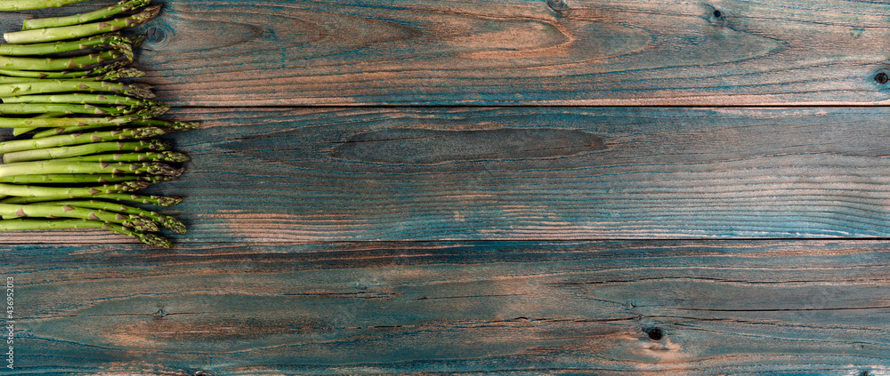 Fresh organic asparagus on faded blue wood planks in overhead view - obrazy, fototapety, plakaty 