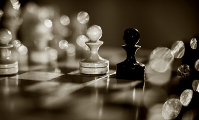 Two pawns - black and white. Wooden chess pieces on the chessboard.