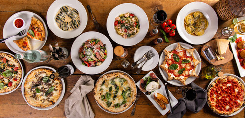 Big dinner table with italian food, pizzas and pastas