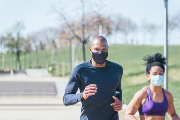 Wall Mural - Man and woman with mask running in a park.