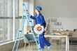 © Pixel-Shot - Young female electrician with cables on ladder in room