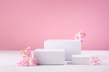 Wall Mural - White rectangle podiums different size for presentation cosmetic produce or goods with fresh spring flowers and pastel pink background. Template for advertising.