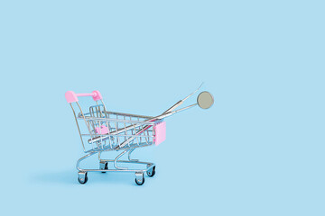 dental tools mirror and probe in shop in cart basket trolley on blue background. medical supplies. delivery, purchase, sale, shopping online. oral care. examination and treatment of teeth. copy space