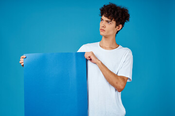 guy in a white t-shirt holding a poster mockup advertising blue background