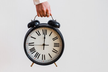 Wall Mural - Female hand holding a big vintage alarm clock