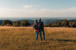 © Zoran Zeremski - Active senior couple hiking in nature with backpacks, enjoying their adventure at sunset.