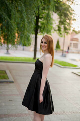 Sticker - Young attractive woman in a black dress posing in the green park