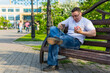 © Николай Чекалин - A young man in white sitting on a park bench accidentally spills hot coffee on his pants during lunch